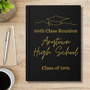 May include: A black hardcover book featuring a gold line-art graduation cap icon and the text 50th Class Reunion Anytown High School Class of 1976 printed in gold lettering on the front cover.