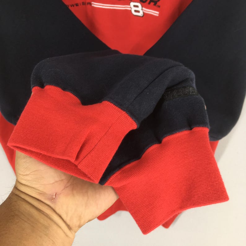 Puede incluir: Sudadera roja y azul marino con el n&uacute;mero 8 y texto. Los pu&ntilde;os y el dobladillo inferior son rojos, mientras que las mangas y la parte superior del cuerpo son azul marino. La sudadera est&aacute; hecha de un material suave y c&oacute;modo.