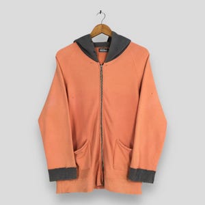 May include: A white ceramic mug with a black handle and the text "But First, Coffee" in a bold, black font. The mug is set against a blurred background, suggesting a cozy setting. The mug appears to be approximately 4 inches tall.