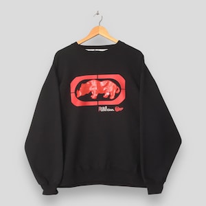 May include: A black long-sleeve sweatshirt featuring a large red graphic on the chest. The graphic displays a stylized rhinoceros silhouette inside a rectangular frame, with the text Ecko Function printed in red below the main design.