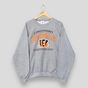 May include: A heather gray crewneck sweatshirt featuring the Cincinnati Bengals team name in orange and black lettering, with the team's tiger-striped B logo in the center and the text National Football League printed below on the front.