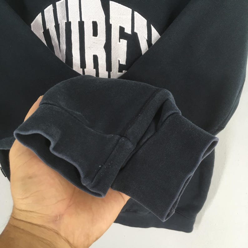 May include: A dark navy blue long-sleeve sweatshirt featuring a ribbed cuff and a large white arched graphic print on the chest that displays the partial text "VIRE". The garment is constructed with a crew neckline and a soft fabric finish.
