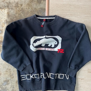 May include: Black sweatshirt with the Ecko Unltd. logo, featuring a white rhinoceros inside a white rectangle. The words "ECKO FUNCTION" are above and below the logo in white, with a red "72" on the right.