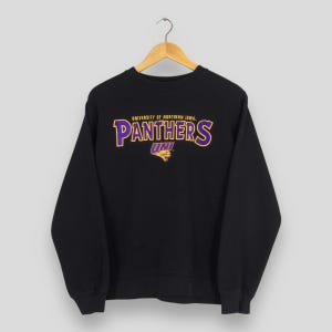 May include: Black crewneck sweatshirt with the text "UNIVERSITY OF NORTHERN IOWA PANTHERS UNI" in gold and purple. The sweatshirt is hanging on a wooden hanger.