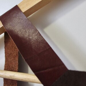 Puede incluir: Un estante de pared de madera con dos correas de cuero marr&oacute;n. El estante est&aacute; dise&ntilde;ado para sostener art&iacute;culos como sombreros, bufandas o bolsos.