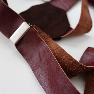 Puede incluir: Primer plano de un par de tirantes de cuero marr&oacute;n con un clip de metal plateado. Los tirantes est&aacute;n hechos de dos tipos diferentes de cuero, uno liso y otro texturizado.