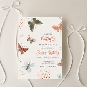 May include: A cream-coloured birthday invitation featuring watercolour butterflies in orange, green, and blue. The text reads "Our Little Butterfly is Turning Two!" and invites guests to celebrate Olivia's birthday on 2 May, 2026, at 3:00 PM.