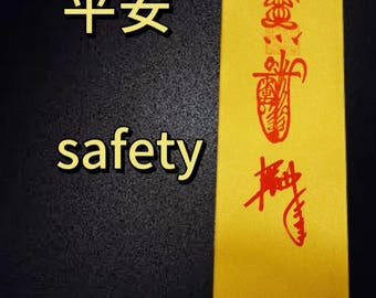 May include: A yellow paper scroll with red Chinese characters that translate to "safety" in English. The scroll has a red seal with the Chinese character for "heaven" on it.