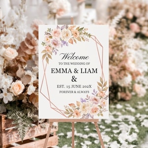 Könnte beinhalten: Ein Hochzeits-Willkommensschild auf einer Holzstaffelei. Das Schild zeigt die Namen EMMA & LIAM, mit floralen Akzenten in Pfirsich, Rosa und Lavendel. Der Text lautet "Willkommen" und "Für immer & ewig".