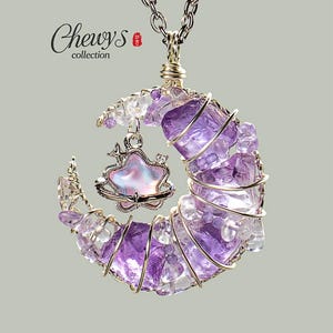 May include: A handcrafted necklace featuring a crescent moon pendant made of purple and clear crystals, wire-wrapped in gold. A star-shaped charm with iridescent accents hangs within the moon. The necklace has a silver chain and the text "Chewys collection".
