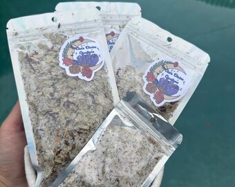 May include: Three silver pouches containing dried herbs and flowers. The pouches have a sticker with the text "Gaia Divine Organics" and a purple crystal design.