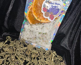 May include: A clear plastic bag filled with white bath salts and dried orange slices. The bag has a sticker with the text "Crate Divine Creations" and a purple crystal design.