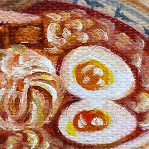 May include: An oil painting of a bowl of ramen featuring a rich red broth, two halved soft-boiled eggs with bright yellow yolks, and textured noodles. The bowl has a light-colored rim with blue decorative markings, and a wooden spoon rests inside.