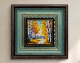 Op de afbeelding: Een vierkant ingelijst schilderij met een bosscène met witte berkenbomen en levendig geel herfstgebladerte. Het kunstwerk zit in een meerlaagse lijst met een donkerbruine buitenrand en een verweerde blauwgroene binnenrand met gouden accenten.