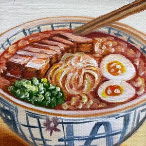 May include: An oil painting of a bowl of ramen featuring a red broth, sliced pork belly, a soft-boiled egg cut in half, and green onions. A pair of wooden chopsticks rests in the bowl. The ceramic bowl has a blue and white grid pattern.
