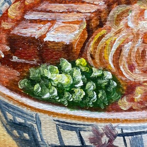 May include: An oil painting of a bowl of food featuring thick slices of brown meat, a pile of bright green leafy vegetables, and translucent yellow onion rings. The bowl has a white base with a dark blue grid pattern and a small floral detail.