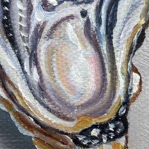 May include: Close-up of an abstract oil painting with a palette of neutral colors. The artwork features swirling brushstrokes in shades of white, gray, brown, and gold, with a central area of soft pink and peach tones. The texture is thick and visible.