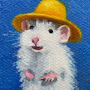 May include: An oil painting of a white rat wearing a yellow hat against a textured blue background. The rat has pink ears, a pink nose, and small paws visible. The brushstrokes are thick and visible, creating a tactile surface on the canvas.