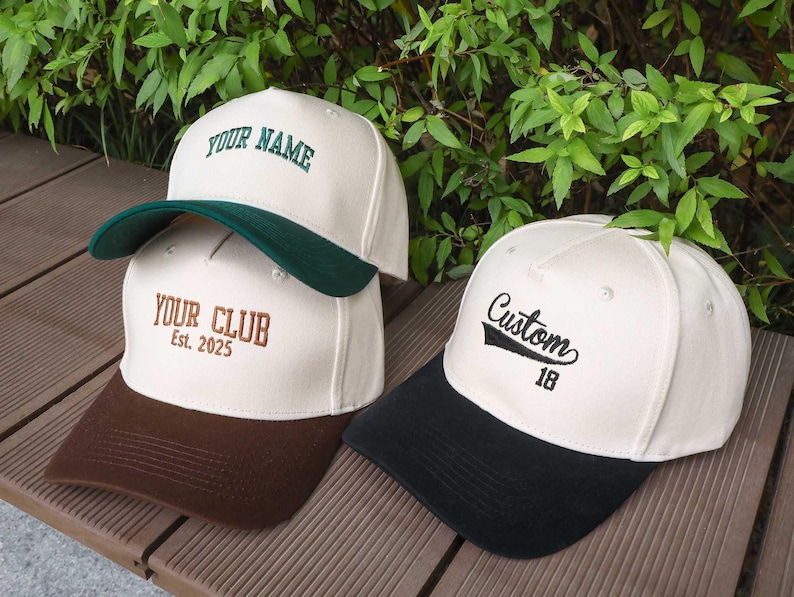 May include: Three baseball caps with custom embroidery. One cap has "YOUR NAME" in green, another says "YOUR CLUB Est. 2025" in brown, and the third says "Custom 18" in black. Each cap has a different colored brim.