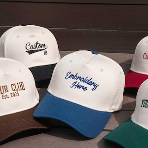 May include: A collection of white baseball caps with colored brims. Each cap features custom embroidery, including phrases like "Custom 18", "Your Club Est. 2025", "Embroidery Here", "Custom Text", and "Your Name".