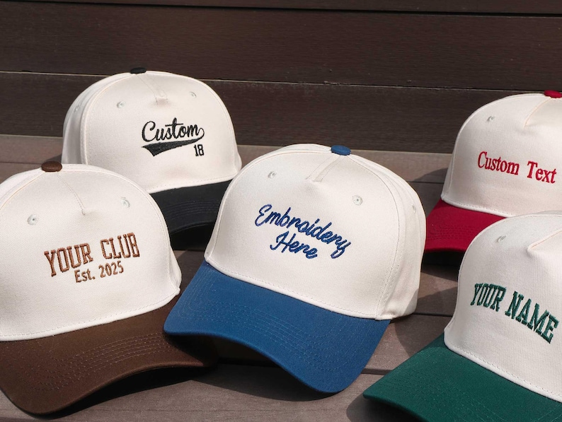May include: A collection of white baseball caps with colored brims. Each cap features custom embroidery, including phrases like "Custom 18", "Your Club Est. 2025", "Embroidery Here", "Custom Text", and "Your Name".