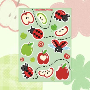 Puede incluir: Una hoja de pegatinas con un fondo verde claro presenta ilustraciones de manzanas rojas y verdes, mariquitas, tréboles y rodajas de manzana. El texto "aya_fixon_friday" está en la esquina superior derecha. Líneas discontinuas conectan algunas de las imágenes.