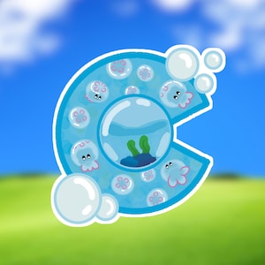 May include: A whimsical sticker featuring a blue letter "C" filled with cartoon jellyfish and bubbles. Inside the letter is a small aquarium scene with plants. The background is a blurred image of a blue sky and green grass.