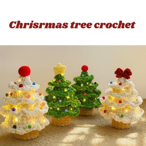 Puede incluir: Cuatro árboles de Navidad de ganchillo hechos a mano en varios colores. Los árboles son blancos, verdes y crema, con elementos decorativos como pompones, estrellas y lazos. Los árboles están iluminados con pequeñas luces y se asientan sobre una base beige. El texto "Chrisrmas tree crochet" está en la parte superior.