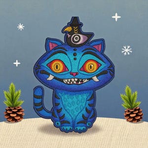 May include: Embroidered patch featuring a blue cat with orange eyes and sharp teeth, wearing a bird hat. The cat has intricate patterns and is set against a light blue background with snowflakes and pinecones.