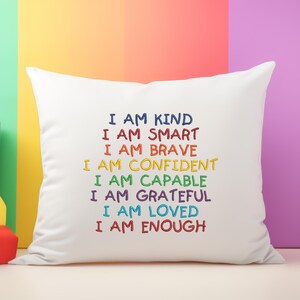 May include: White pillow with the text "I am kind, I am smart, I am brave, I am confident, I am capable, I am grateful, I am loved, I am enough" embroidered in rainbow colors.