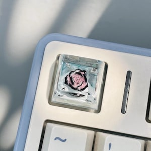 May include: A set of three ceramic mugs with a speckled, matte finish. The mugs are in shades of cream, light gray, and dark gray. Each mug has a simple, minimalist design and a rounded handle.