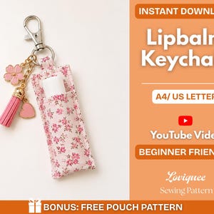 May include: A fabric lip balm keychain holder featuring a pink floral pattern, attached to a silver metal lobster clasp. The keychain includes a pink tassel, a pink heart charm, and a pink flower charm. Text reads: INSTANT DOWNLOAD Lipbalm Keychain A4/ US LETTER YouTube Video BEGINNER FRIENDLY Loviquee Sewing Pattern BONUS: FREE POUCH PATTERN.