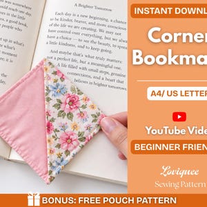 Puede incluir: Un marcapáginas de esquina triangular con un lado de tela rosa sólida y un lado con estampado floral de flores rosas, azules y amarillas sobre fondo blanco. El marcapáginas está colocado sobre una página de libro abierta con texto.