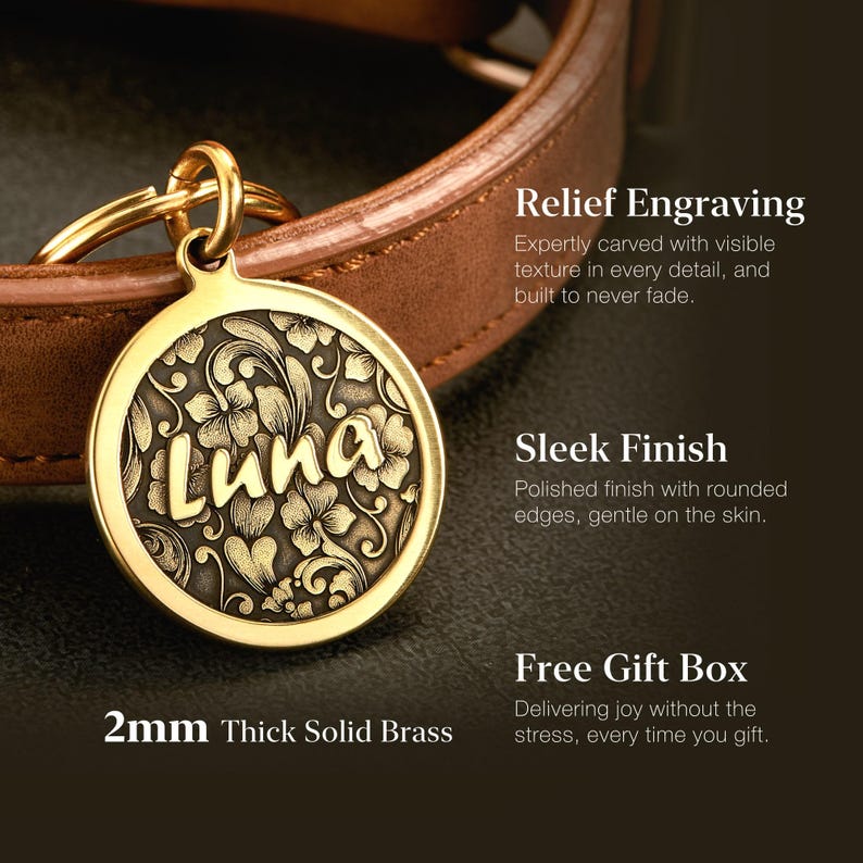 May include: A round, 2mm thick solid brass pet tag featuring a relief-engraved floral pattern and the name Luna in raised lettering. The tag is attached to a brown leather collar by a gold-colored metal ring, showcasing a polished finish.