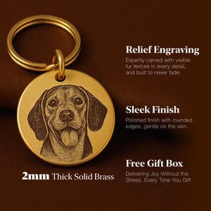 K&ouml;nnte beinhalten: Ein goldfarbener, runder Schl&uuml;sselanh&auml;nger mit einem detailliert eingravierten Bild eines Hundegesichts. Der Schl&uuml;sselanh&auml;nger besteht aus 2 mm dickem massivem Messing und tr&auml;gt den Text "Relief Engraving", "Sleek Finish" und "Free Gift Box".