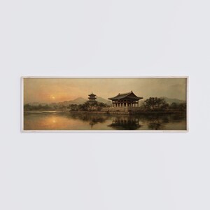May include: A panoramic landscape painting in a light-colored wooden frame depicting a traditional East Asian pavilion and a multi-story pagoda situated on an island in a calm lake at sunset, with soft golden light reflecting on the water surface.