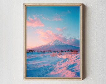 May include: A framed print of a snow-covered landscape with a mountain under a blue sky with pink clouds. The mountain is in the distance, and the foreground is covered in snow. The frame is a light wood color.