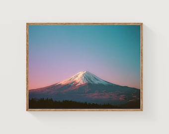 Può includere: Una stampa incorniciata del Monte Fuji all'alba. La montagna innevata si staglia contro un cielo sfumato di blu, rosa e arancione. Una foresta scura si trova alla base della montagna.