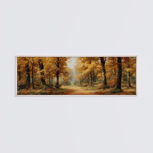 Può includere: Un dipinto paesaggistico panoramico in una cornice di legno chiaro, che raffigura un denso sentiero boschivo durante l'autunno. La scena presenta alberi alti con fogliame dorato e arancione vibrante, tronchi scuri e una luce soffusa e nebbiosa.