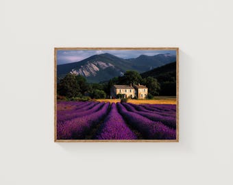 Op de afbeelding: Een ingelijste landschapsafdruk met een veld met paarse lavendelrijen die naar een stenen huis leiden. Bergen en bomen zijn op de achtergrond onder een blauwe lucht. Het kunstwerk zit in een houten lijst.