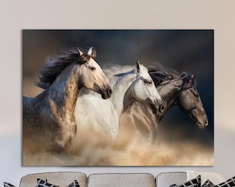May include: A canvas print featuring three horses running. The horses are in shades of gray, white, and black, with flowing manes and tails. The background is a mix of dark and light tones, with a dusty effect.