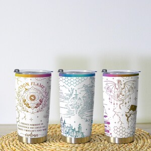 May include: Three stainless steel insulated tumblers with fantasy-themed designs. One features the text "IRON FLAME" and a quote. Another displays a map with a sword. The third has a dragon illustration. Each has a colored rim.