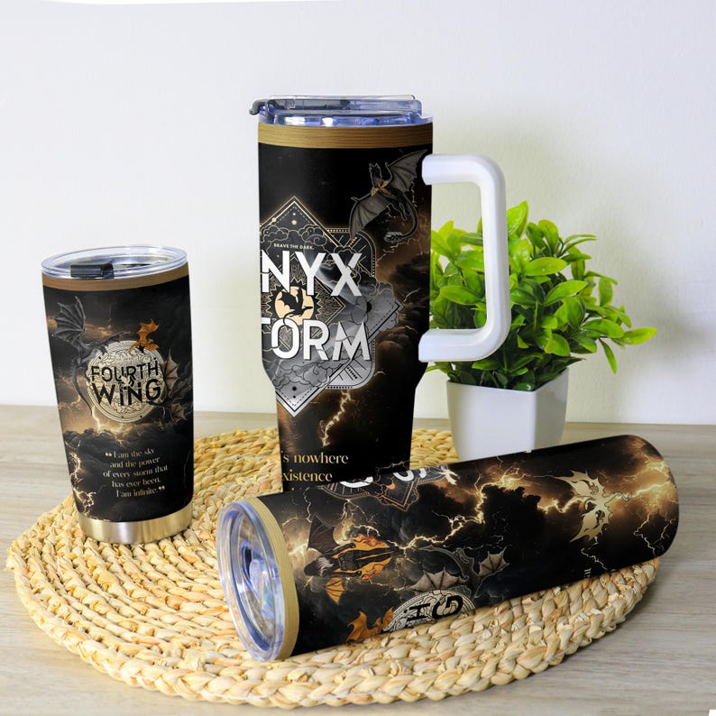 May include: A collection of insulated tumblers with fantasy-themed designs. One tumbler features the text "FOURTH WING" and a dragon graphic. Another displays "NYX STORM" with a bat and lightning. The tumblers are black with gold and white accents.