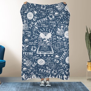 Könnte beinhalten: Eine marineblaue Decke mit einem weißen Fantasy-Muster. Das Design enthält Texte wie "Feyre darling", "City of Starlight" und "Bat Boys" sowie Illustrationen eines Schlosses, eines Drachen und anderer Fantasy-Elemente.