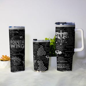 May include: Three black insulated tumblers with white graphics and text. The largest tumbler has a handle and the text "SHOULD I GET THE INGLEADER?". The middle tumbler has a dragon scale design. The smallest tumbler has the text "FOURTH WING".