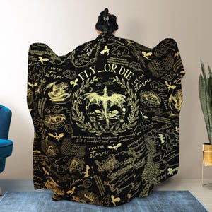 May include: Black hooded blanket with gold dragon and text design. The blanket features a central dragon illustration with the words "FLY...OR DIE" and "I AM THE STORM". Additional text and dragon graphics are scattered across the blanket.