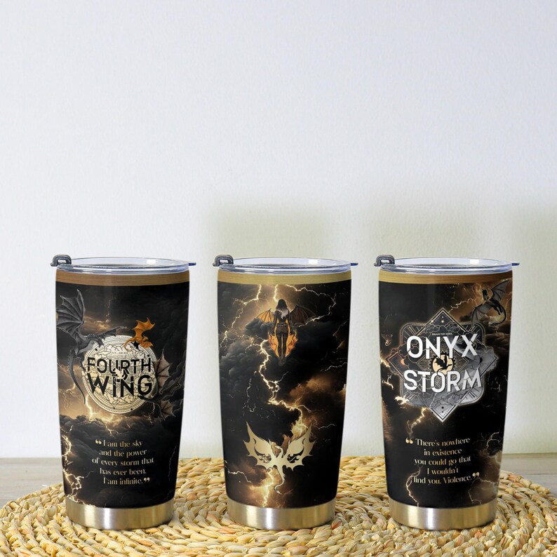 May include: Three stainless steel insulated tumblers with black and gold designs. Each tumbler features a different design with text and illustrations of dragons and a woman with wings. The text includes "FOURTH WING" and "ONYX STORM".