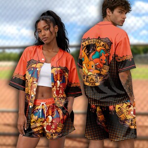 May include: An orange and black button-down baseball jersey and matching shorts set featuring a graphic print of Charizard, Charmander, and a handheld game console with the text I CHOOSE FIRE and CHARIZARD printed on the fabric in a bold design.