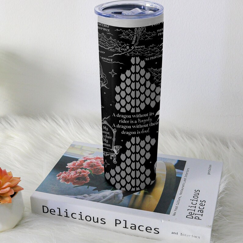 May include: A stainless steel travel tumbler with a black background featuring a dragon scale design and text. The text reads "A dragon without its rider is a tragedy. A dragon without their dragon is dead." The tumbler is cylindrical and has a silver lid.