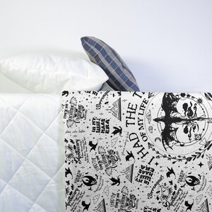 May include: A white and black patterned blanket with text and illustrations. The blanket features phrases like "I had the time of my life" and "Fighting Dragons with you." Decorative pillows are in the background.